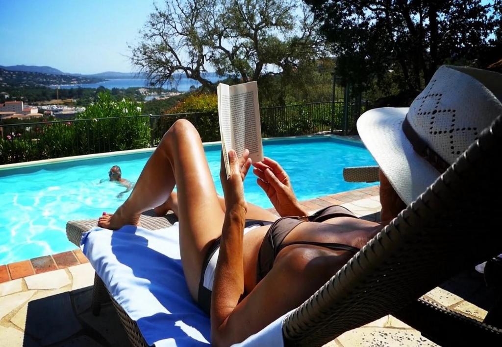 维琪奥港里赛塔公寓的躺在椅子上看书的人在游泳池旁