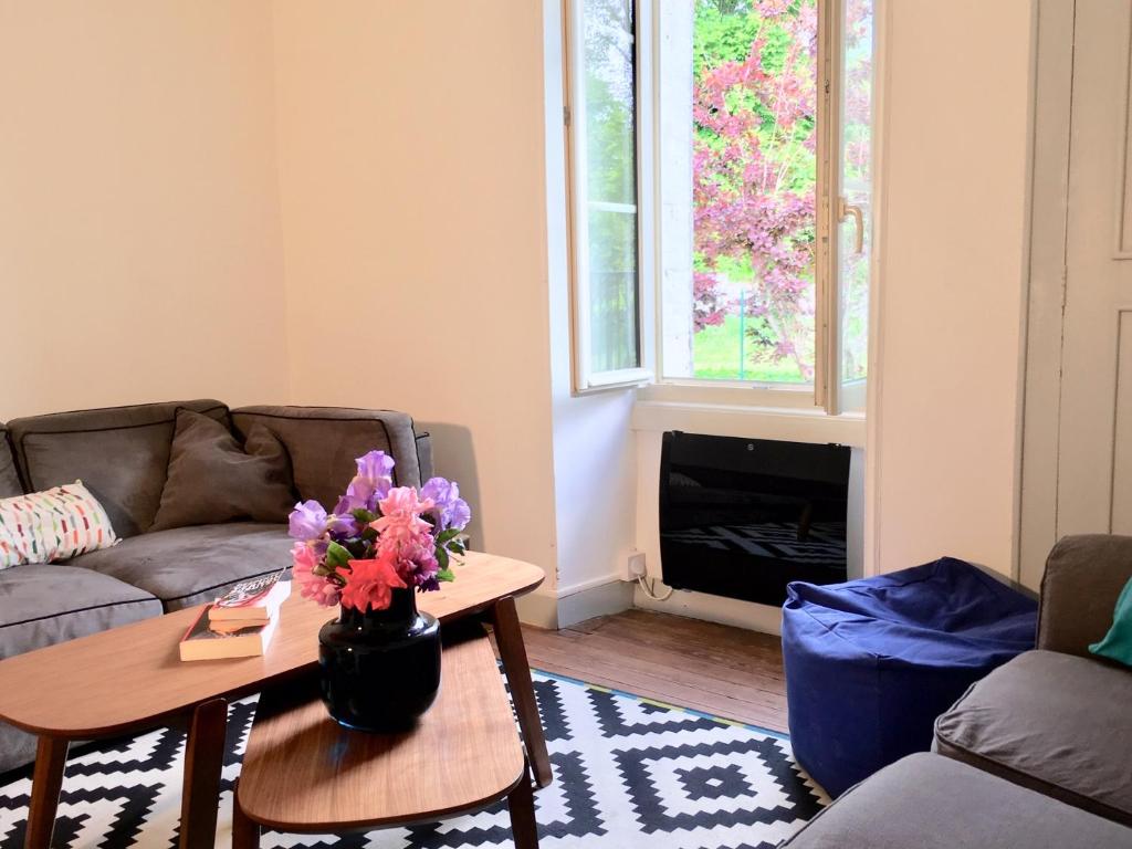 Nuits-sur-ArmançonLa maison des amis的客厅配有沙发和鲜花桌