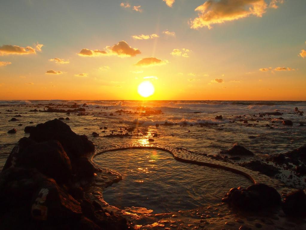 FukauraKoganezaki Furofushi Onsen的海滩上的日落,水中心