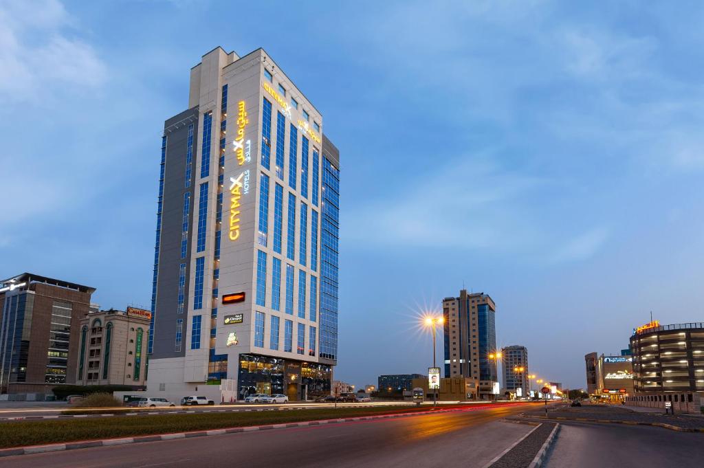 拉斯阿尔卡麦Citymax Hotel Ras Al Khaimah的夜幕降临的城市街道上一座高楼