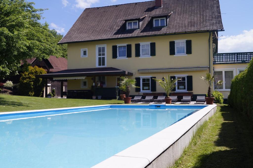 克拉根福Pension DOBERNIG - CONTACTLESS CHECK IN/STAY的房屋前有游泳池的房子