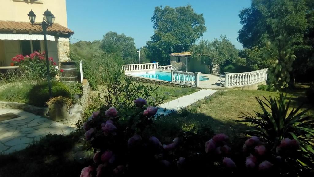 尼姆Le mazet en été - studio en garrigue nimoise的一座花园,花园中设有一座游泳池上的桥梁