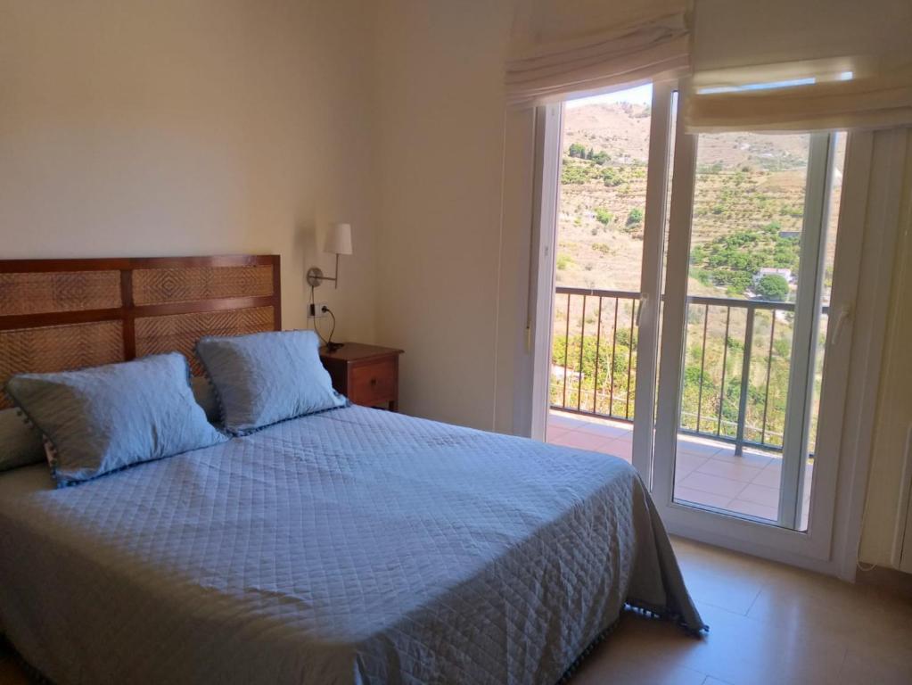 阿尔姆尼卡Bonita casa de vacaciones en Almuñécar的一间卧室配有一张蓝色的床和一个阳台