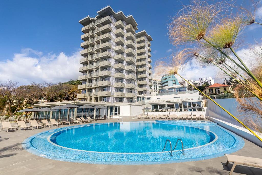 丰沙尔Allegro Madeira - Adults Only的一座大型建筑,在一座建筑前设有一个游泳池