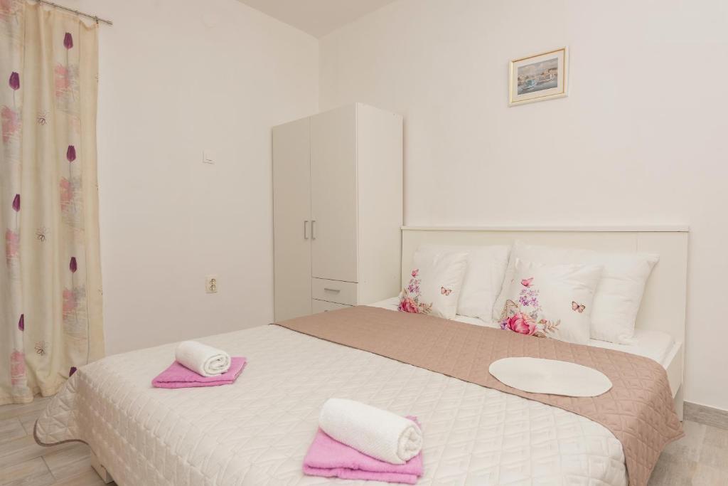 马卡尔斯卡Apartmani Sol的一间卧室配有一张大床,上面有粉红色的毛巾