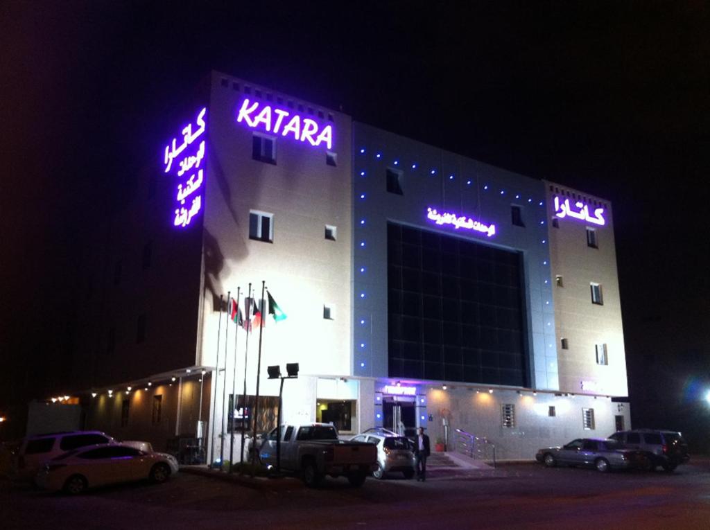 利雅德卡塔拉公寓式酒店的一座晚上有 ⁇ 虹灯标志的建筑