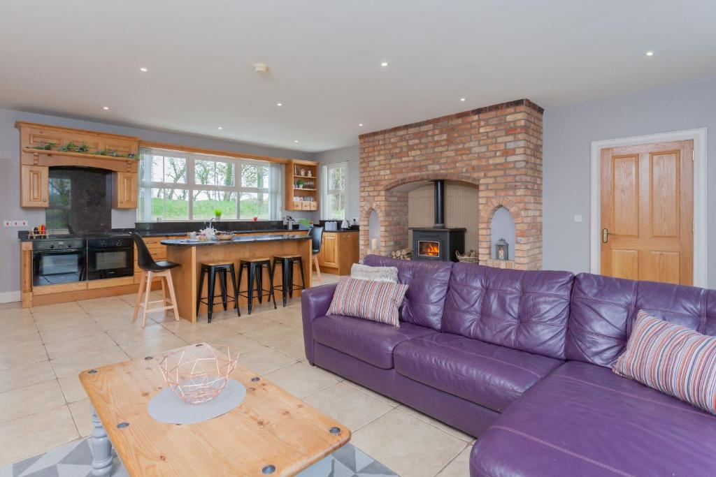 巴利米纳Glenside Lodge的一间带紫色沙发的客厅和一间厨房