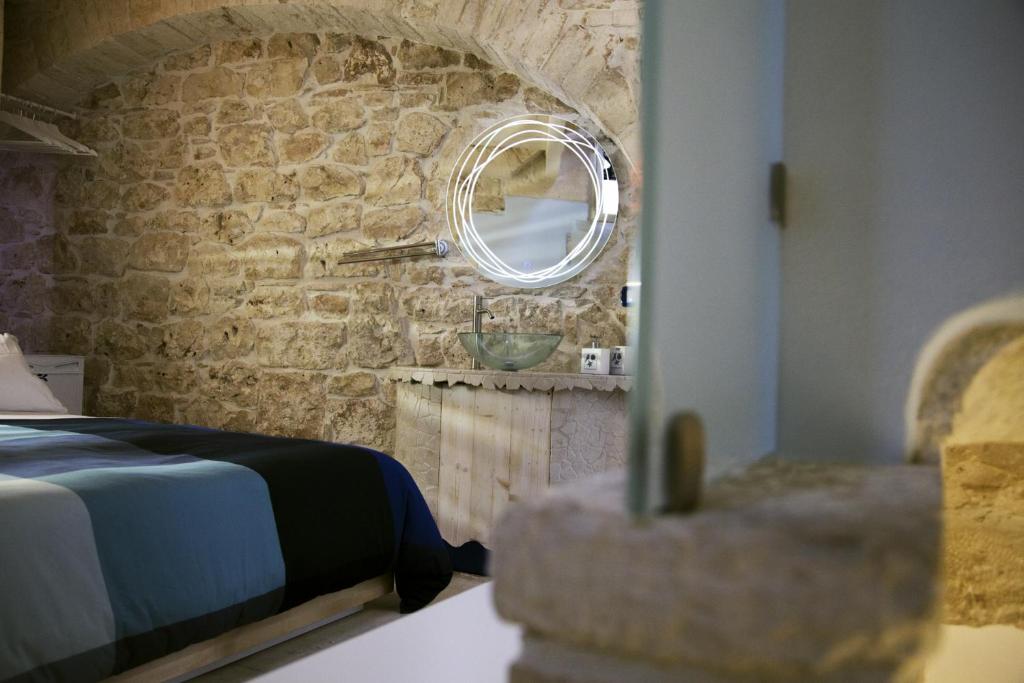 普蒂尼亚诺Vico Santa Maria的一间卧室设有石墙、一张床和镜子