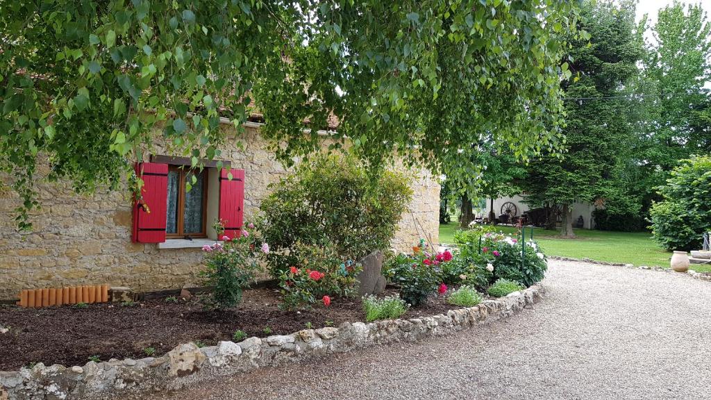 PrigonrieuxChambres d'Hotes Carpediem的一座房子前面有红窗和鲜花