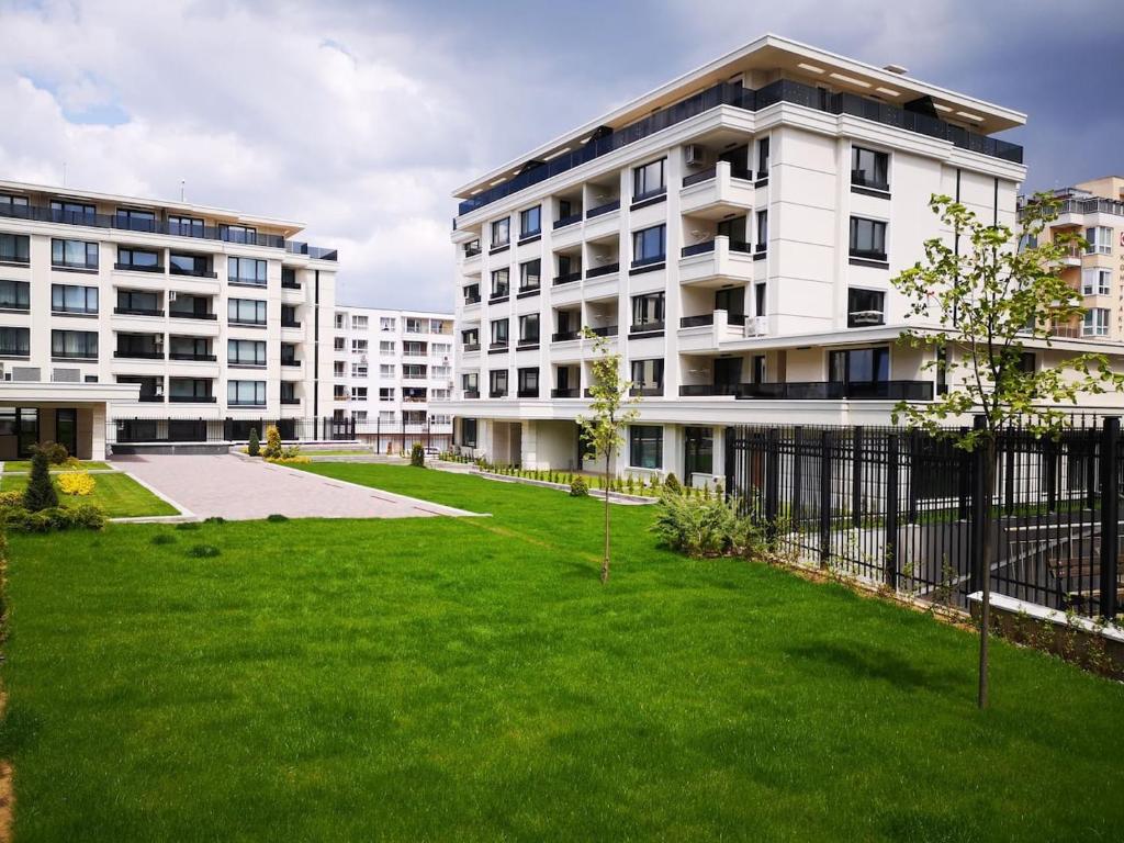 索非亚Business and Leisure apartments in Mladost 2 with FREE Garage的一座白色的大建筑,前面有一个绿色的草坪