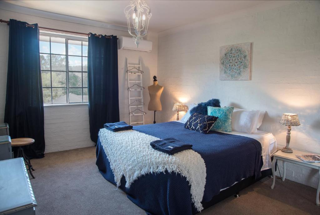 YarramalongAngel Sussurri的一间卧室配有一张带蓝色床单的床和一扇窗户。