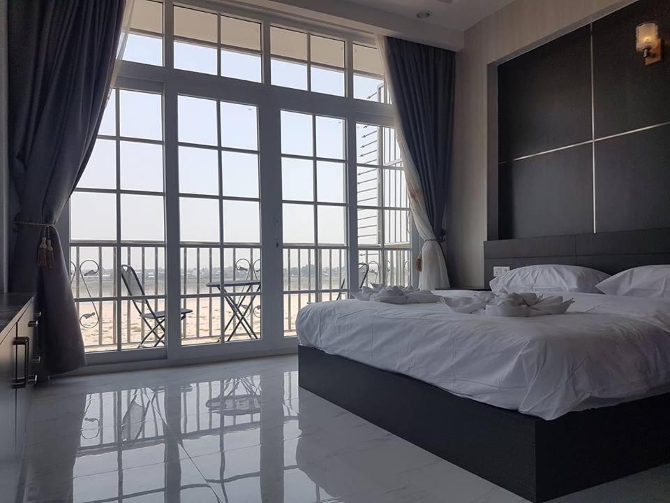 万象Sunset Mekong Apartment的一间卧室设有一张大床和一个大窗户
