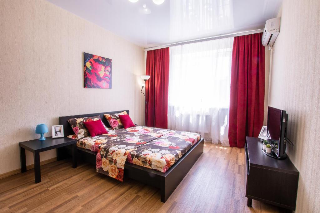 克拉斯诺达尔Апартаменты у Парка Краснодар на Восточно-Кругляковской的一间卧室配有床和红色窗帘的窗户