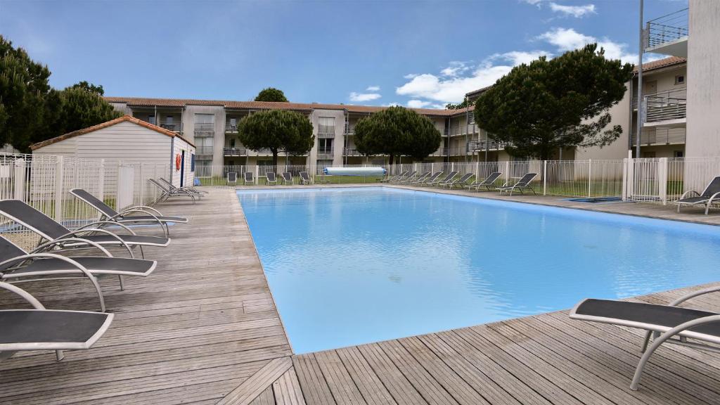 拉戈尔瓦坎斯奥勒 - 城堡庄园 - 拉罗谢尔/雷岛公寓式酒店的木制甲板上带椅子的大型游泳池