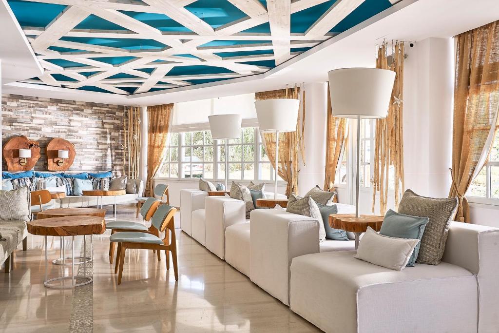 卢特拉Kythnos Bay Hotel的客厅配有白色家具和蓝色天花板。