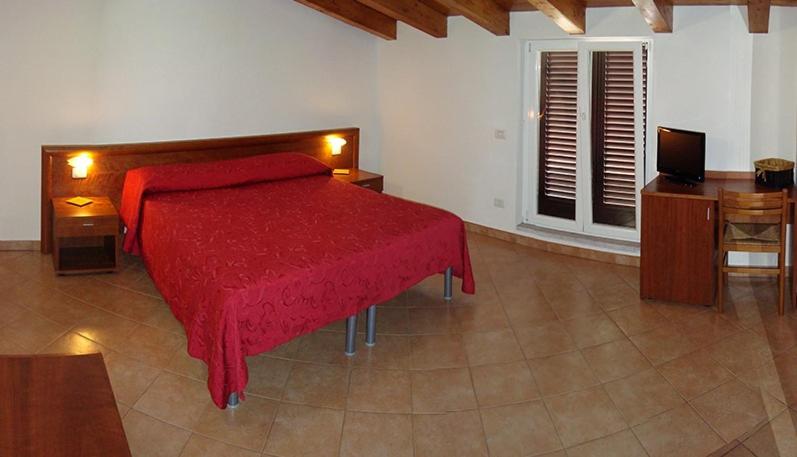 LuniAlbergo Antica Luni的一间卧室配有红色的床和电视