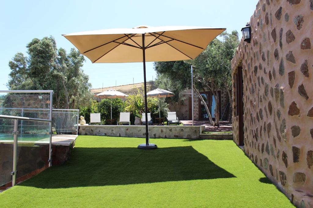 因赫尼奥Villa Cantos Colorados的一个带雨伞和绿草的庭院