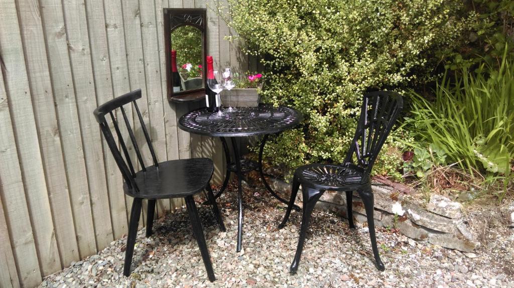 海伦斯堡Black Stair Cottage的两张黑色椅子和一张带鲜花的桌子