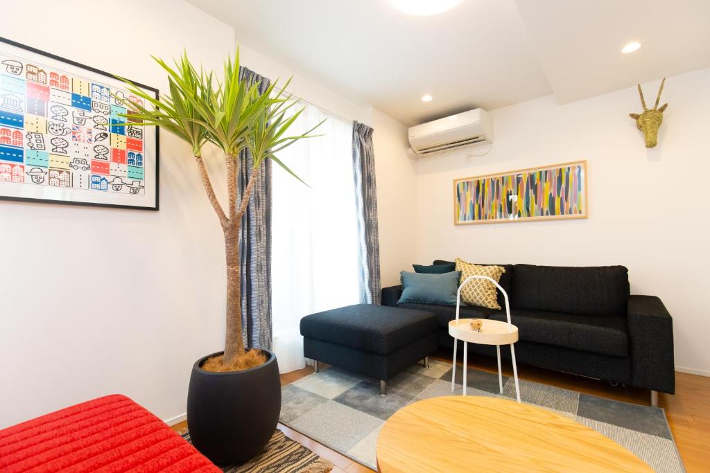 东京Sangen-jaya House-O的一间客厅,配有黑色的沙发和棕榈树