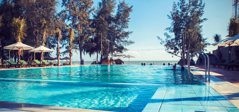 罗夷Cam Bình Resort的海滩旁的游泳池,配有遮阳伞