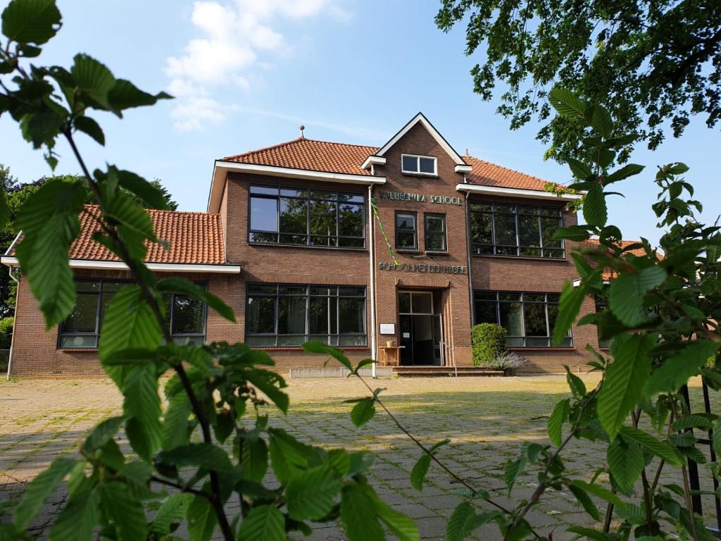 阿尔滕B&B de Wilhelminaschool的一座拥有许多窗户的大型砖砌建筑