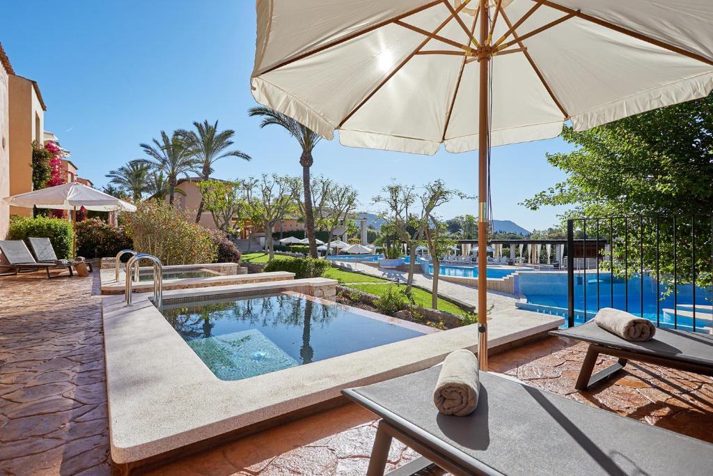 松塞尔韦拉Pula Suites Boutique Resort的一个带遮阳伞和桌子的游泳池以及游泳池