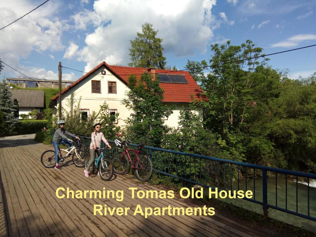 VisokoTomas Old House - River Apartments的两个人骑着自行车在房子前面的桥上骑