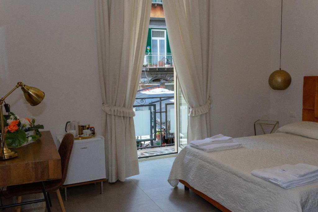 那不勒斯“A piazzetta”的一间卧室配有一张床、一张桌子和一个窗户。