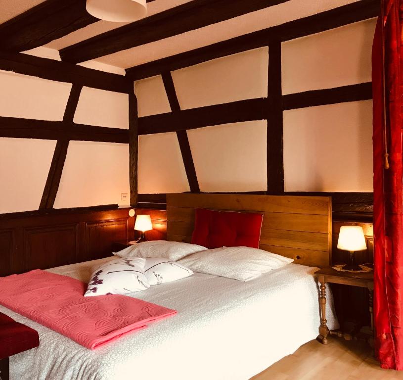 阿梅尔斯克维AUX DEUX CIGOGNES AMMERSCHWIHR的卧室配有带红色枕头的大型白色床