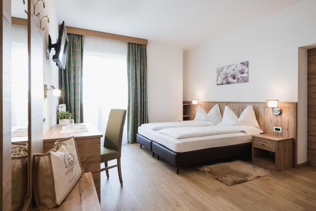 阿拉巴Laguscei Dolomites Mountain Hotel的配有一张床和一张书桌的酒店客房