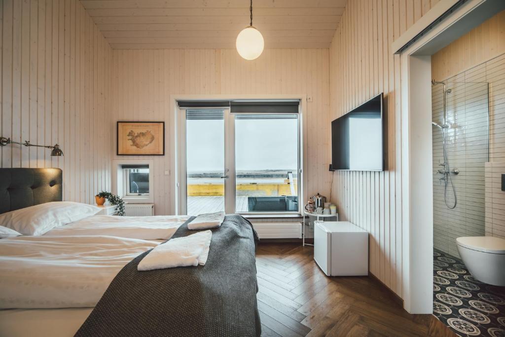 GerdiEkra Glacier Lagoon的一间卧室配有一张床、一个浴缸和一台电视。