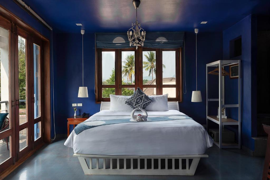 琅勃拉邦英迪格之屋酒店的蓝色的卧室设有床和窗户