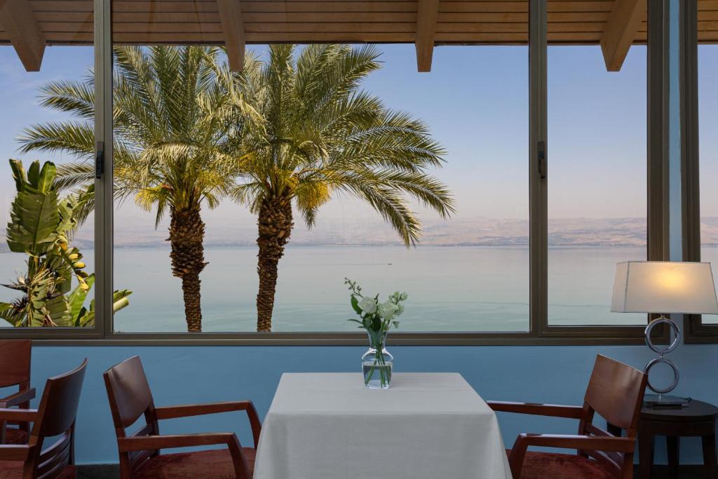 提比里亚太巴列所罗门王酒店的一间设有桌子和棕榈树的用餐室
