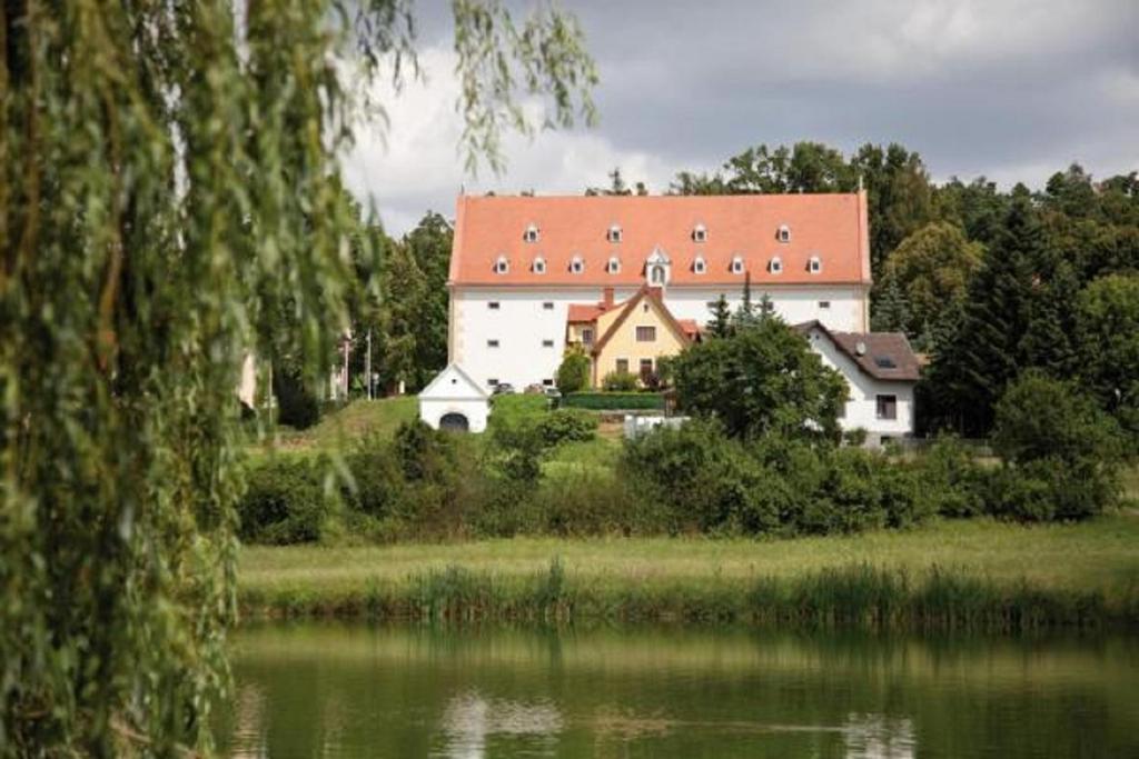 盖拉斯Schüttkasten Geras的一座白色的大建筑,有红屋顶,毗邻湖泊