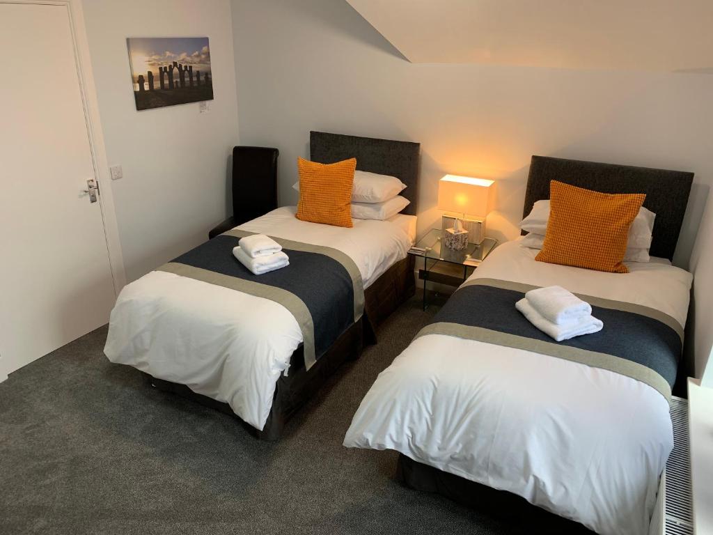 缪勒夫奥德Muir Bank的一间卧室配有两张带橙色和白色枕头的床