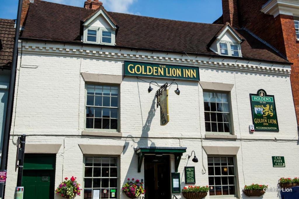 布里奇诺斯The Golden Lion Inn的一座白色的建筑,上面有金狮旅馆标志