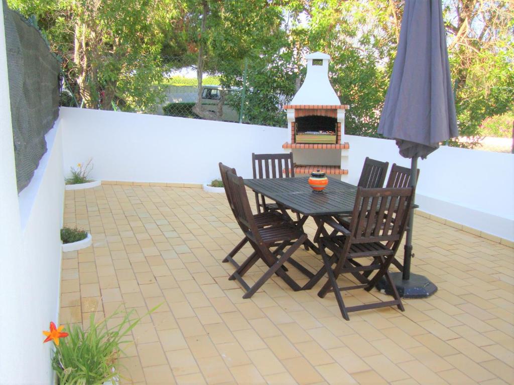卢斯Belinha Guest House的一个带桌椅和烧烤架的庭院