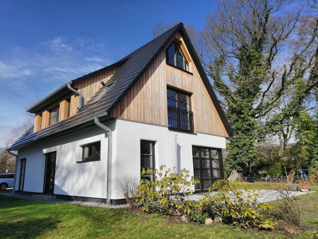 阿伦斯霍普Darßer Strandgut - Haus Ahrenshooper Holz的白色房子,有 ⁇ 帽屋顶