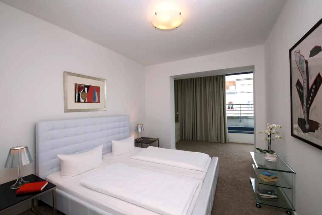 柏林Art'Appart Suiten - kontaktloser Check-In的白色的卧室设有一张白色大床和一个窗户。