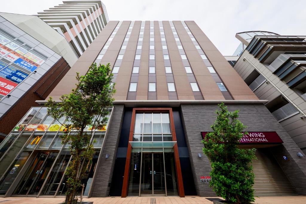神户Hotel Wing International Kobe - Shinnagata Ekimae的前面有树木的高楼