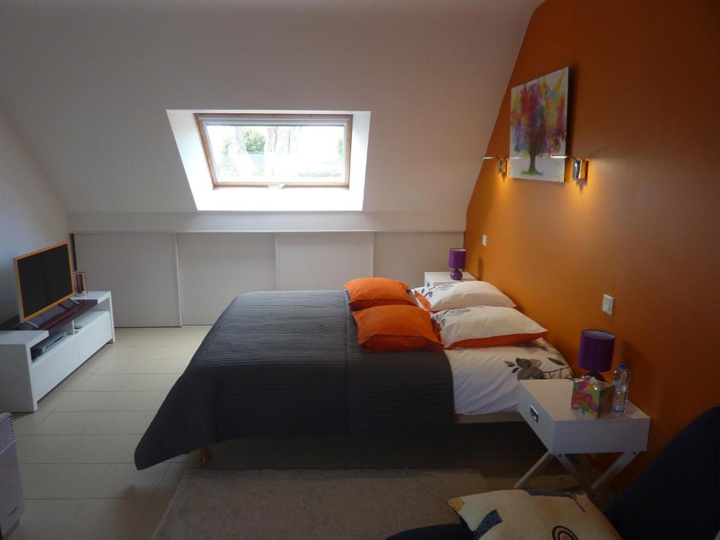圣吉勒达德吕伊Auprès de mon arbre的一间卧室配有带橙色枕头的床和窗户。