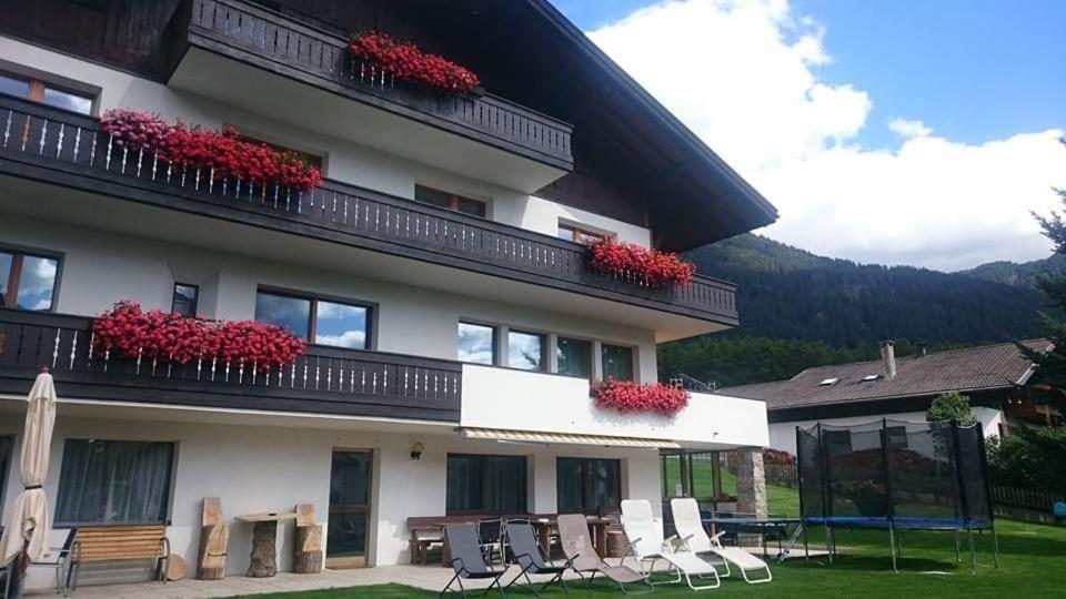 圣瓦伦蒂诺阿拉穆塔Pension Tirol的阳台的建筑,配有椅子和红色鲜花