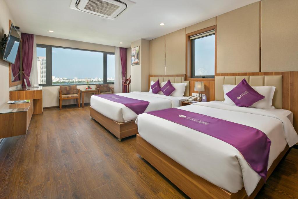 岘港Lavender Riverside Hotel的酒店客房配有两张带紫色枕头的床