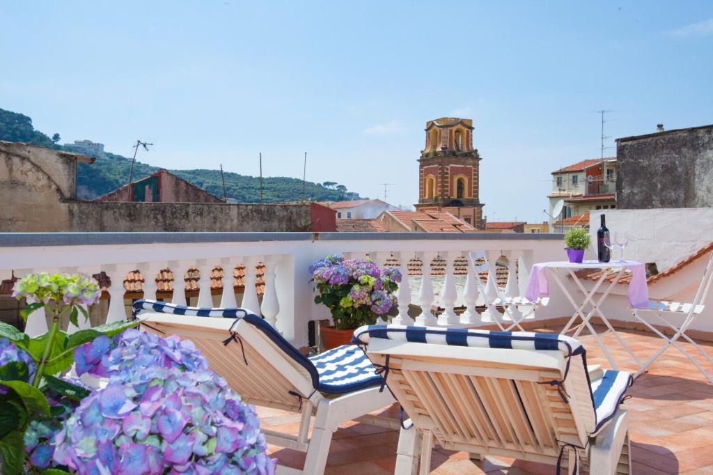 索伦托Sorrento Marida Rooms的阳台配有椅子、桌子和鲜花