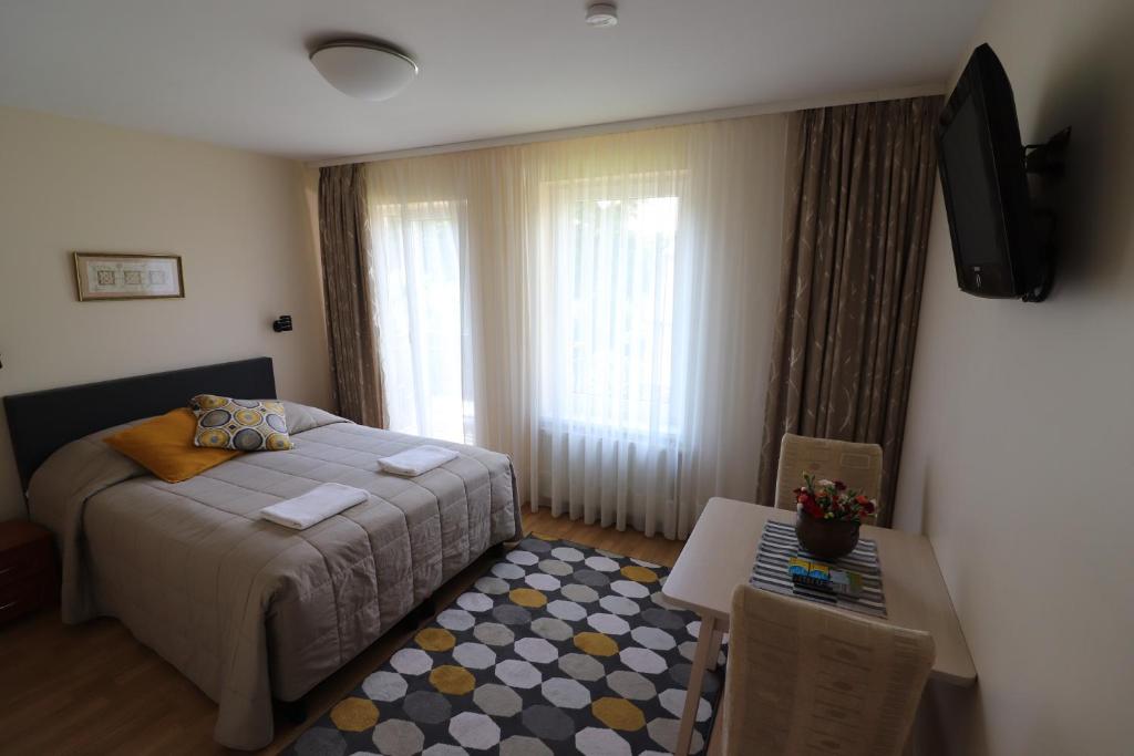 维尔纽斯奈尔加酒店的一间卧室配有一张床、一张桌子和一台电视