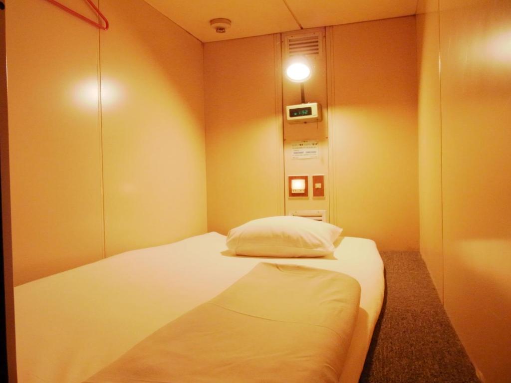 东京Capsule Hotel Block Room的一间小卧室,房间内设有一张白色的床