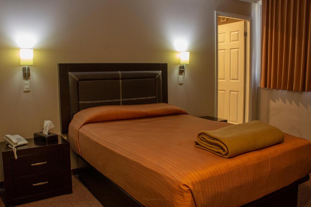 坦皮科BONITTO INN® Tampico Lomas的一间卧室配有一张带橙色毯子的大床