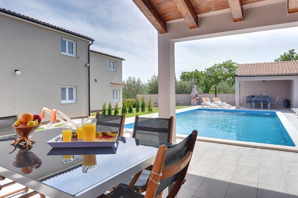 普拉Villa Marcelia的一个带桌椅的庭院和一个游泳池