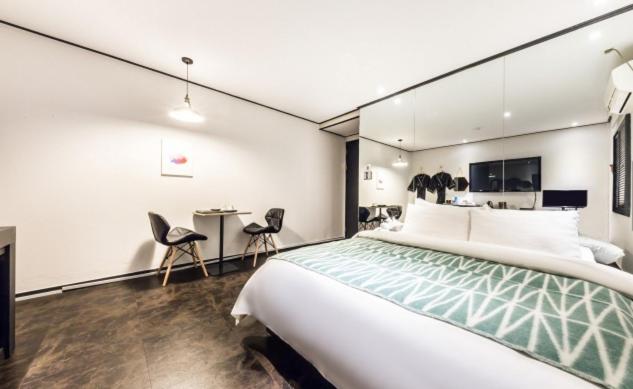 首尔Gugi Motel的一间卧室配有一张大床和两把椅子