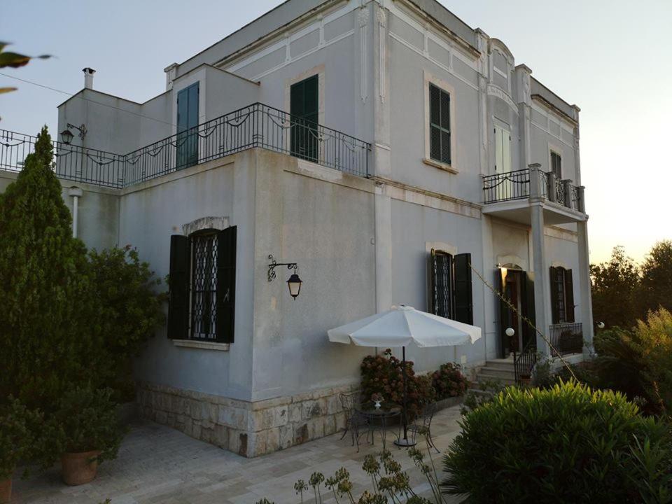 焦维纳佐B&B villa Maria的白色的建筑,配有桌子和雨伞